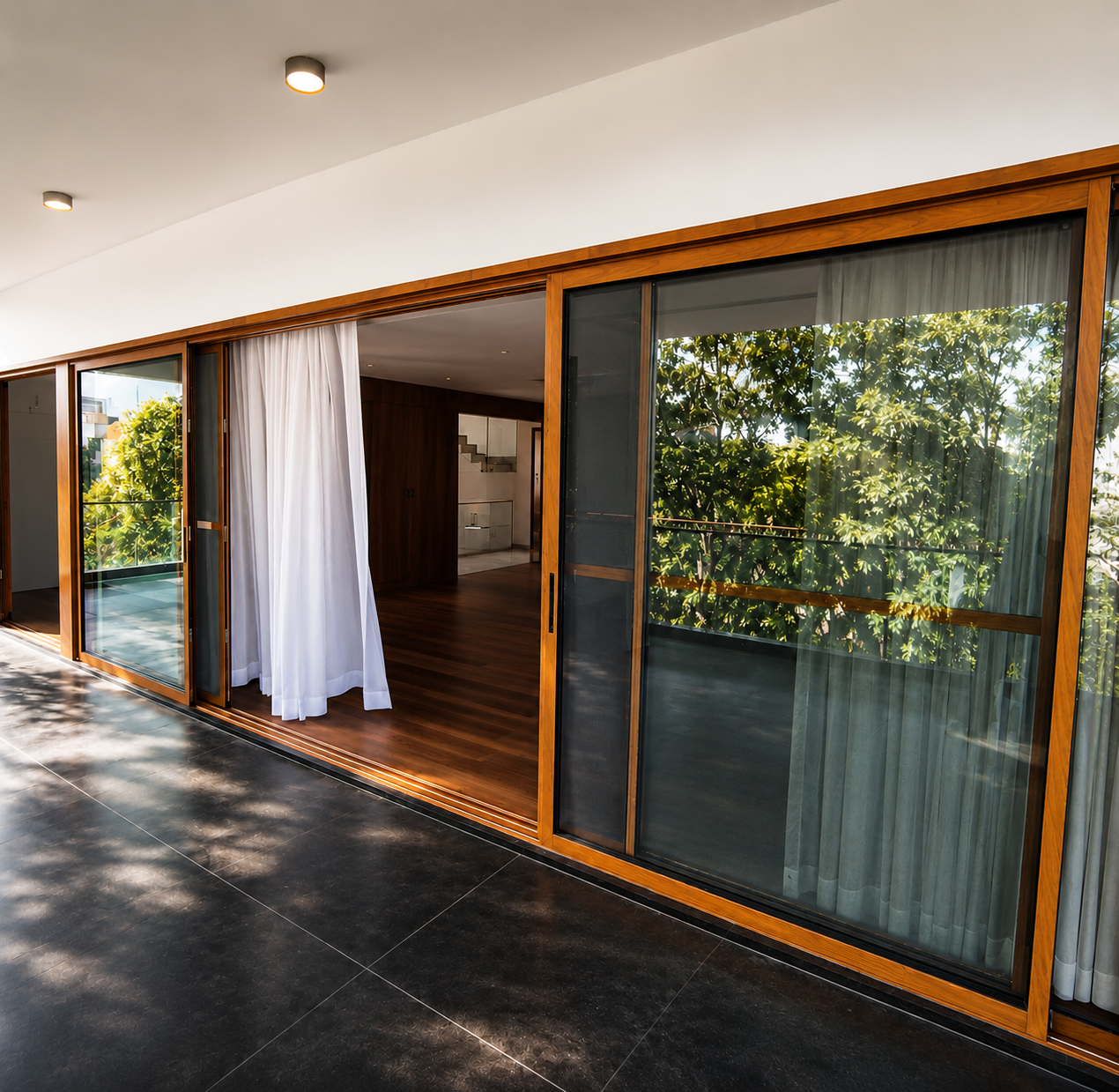 Wide interior shot featuring large SCHON sliding glass panels in a luxury living space with floor-to-ceiling glazing